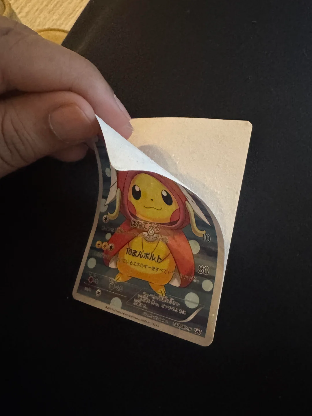 A counterfeit Japanese Pikachu promotional card with its printed layer peeling